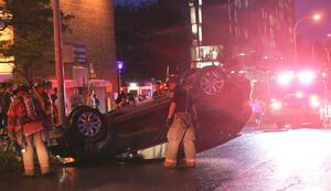 Onlookers watch as the Syracuse Fire Department assesses the damage done to an overturned SUV on Comstock Avenue Monday night. The vehicle flipped after coming in contact with a lamppost. 