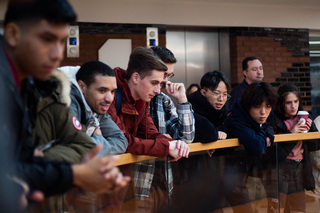 People hover over the railing at Schine Student Center to get a glimpse of the screen and crowded scene. The uproar continually grabbed the attention of people walking by and drew them into the viewing party.